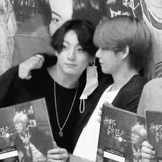 black and white photo of two boys holding books in front of their faces while looking at each other