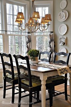 a dining room table with four chairs and a chandelier hanging from the ceiling