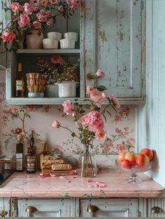 a kitchen with pink flowers on the wall and shelves filled with bottles, glasses, cups, and other items