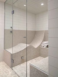 a bathroom with a glass shower door and tiled walls