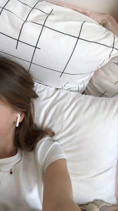 a woman laying on top of a bed next to a white pillow with black lines