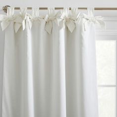 a white curtain with bows hanging from it's side