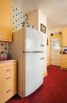 a white refrigerator freezer sitting inside of a kitchen next to yellow cabinets and drawers