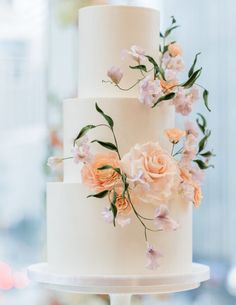 a three tiered white cake with flowers on top