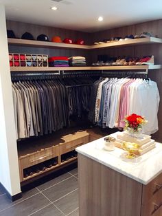 a walk - in closet with clothes and shoes on the shelves, along with an island