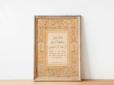 an ornate frame with arabic writing on the front and back, sitting on a wooden table