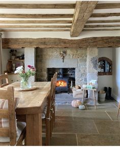 a table and chairs in front of a fire place with flowers on the table next to it