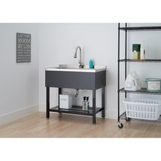 a bathroom sink sitting on top of a wooden floor next to a shelf filled with toiletries