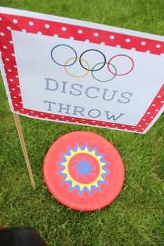 a red frisbee sitting next to a sign on the grass