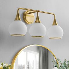 a bathroom light with three lights and a mirror on the wall above it in front of a potted plant