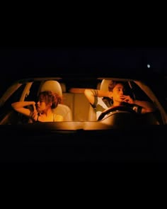 two people sitting in the back seat of a car at night