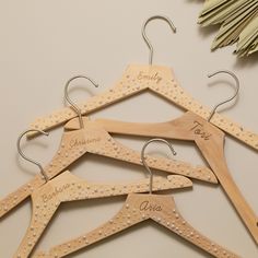 four wooden clothes hangers with personalized names on them next to an ornament