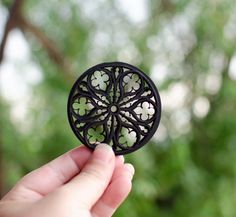 a hand holding a small black object with white flowers on it