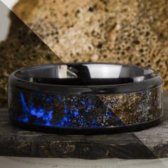 a black and blue ring sitting on top of a rock