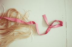 a woman's hair is laying on the floor with a pink ribbon around her neck