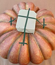 a cake shaped like a pumpkin with a box on it's top and cross marks in the middle