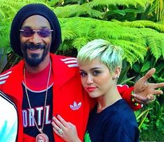 two women and a man are posing for a photo in front of some plants with palm trees