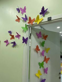 colorful paper butterflies are hanging on the wall next to a door in an office building