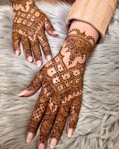 two hands with henna tattoos on them, one is showing the intricate pattern and the other