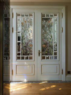 two white doors with stained glass panels and wood flooring in front of the door