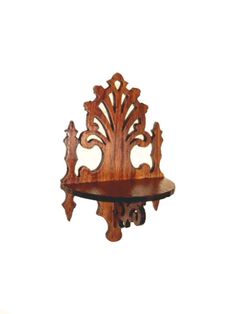 an ornate wooden shelf with carvings on the top and bottom, against a white background