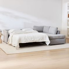 a bed sitting on top of a wooden floor next to a white couch in a living room