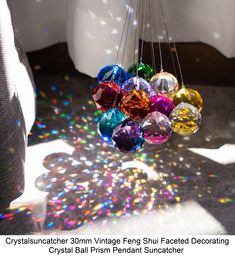 the sun shines brightly through colorful glass balls hanging from a chandelier in a bathroom