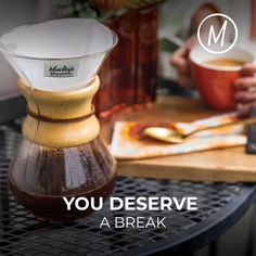 a coffee pot sitting on top of a wooden table next to a cup of coffee