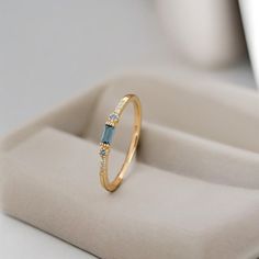 a gold ring with blue and white stones on it sitting on top of a table