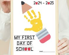 a person holding up a poster with a hand print on it that says my first day of school