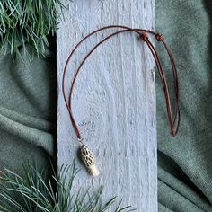 a necklace with an animal print on it sitting next to some pine needles and branches