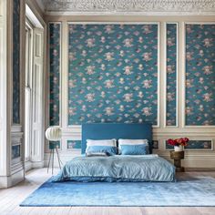 a bedroom with floral wallpaper and blue bedding