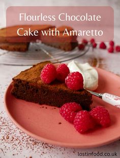 a piece of chocolate cake on a pink plate with raspberries and whipped cream