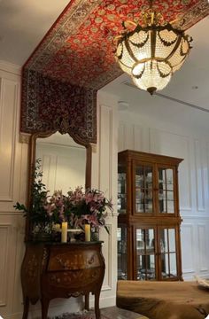 an ornately decorated ceiling in a living room with flowers on the table and a mirror