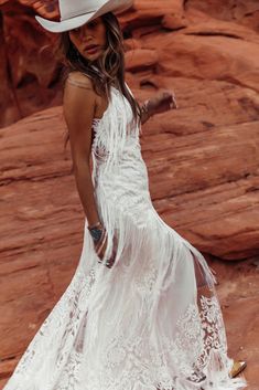 a woman in a white dress and cowboy hat