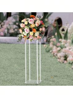 two clear vases with flowers in them on the grass near some pink and yellow flowers