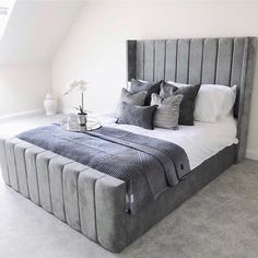 a large bed sitting in the middle of a bedroom next to a white vase with flowers on it