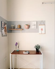 a small table with some flowers on it in a room that has white walls and wood flooring