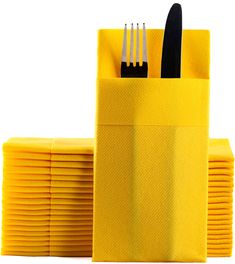 a stack of yellow napkins with forks and knives sticking out of it's holder