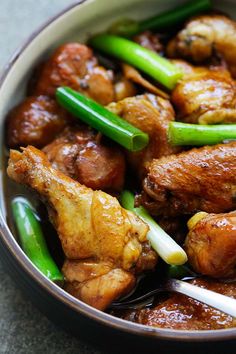 a bowl filled with meat and green beans on top of a table next to chopsticks