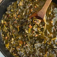 a pan filled with cooked greens and a wooden spoon in the skillet on the stove