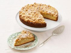 a cake sitting on top of a white table next to a plate with a slice cut out