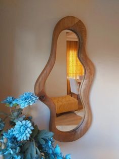 a mirror that is on the wall near a vase with blue flowers in front of it