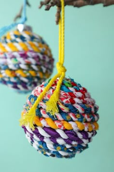 two ornaments hanging from a tree branch with yellow and white yarn on them, one is colorful