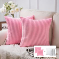 two pink pillows sitting on top of a white couch next to a vase with flowers