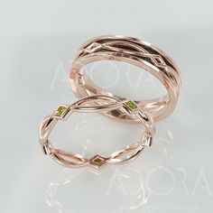 two gold rings with green stones on them are sitting side by side against a white background