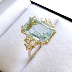 an aqua and yellow diamond ring in a box with white furnishing on the floor