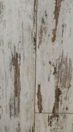 an old white wooden wall with peeling paint on it's sides and rusted edges