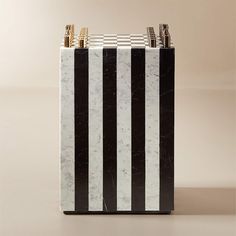 a black and white marble pen holder with gold accents on the top, in front of a beige background