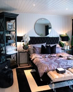 a bedroom with a large bed, black and white rugs on the floor and shelves